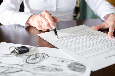 Woman reading a car purchase contract in car dealershipの写真素材