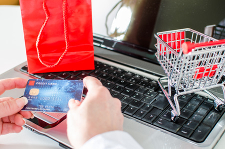 Woman holding a credit card over a laptop before buying onlineの写真素材