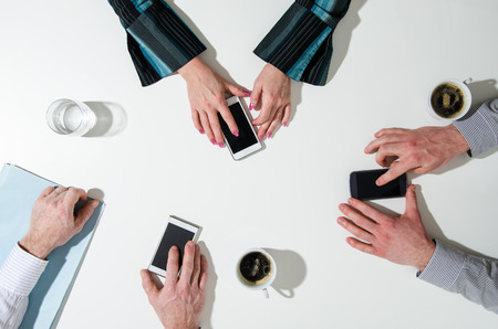 Business people using their smatphone, top viewの写真素材