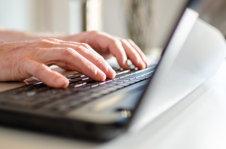 Hand typing on a laptop, side viewの写真素材