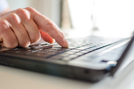 Hand typing on a laptop, side viewの写真素材