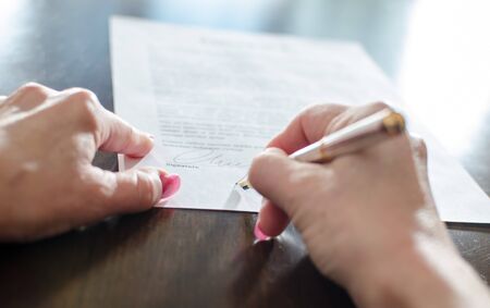 Hand of a woman signing a contractの写真素材