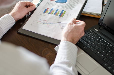 Businessman analysing economic graphs at officeの写真素材
