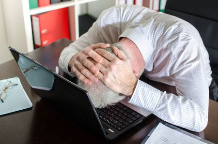 Overworked businessman holding his head in his handsの写真素材