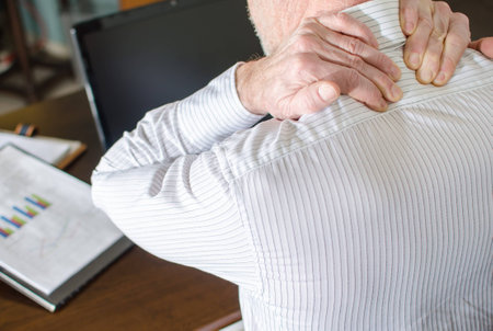 Businessman with neck pain at officeの写真素材