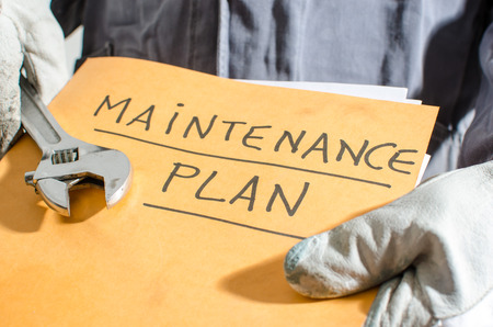 Worker holding a folder of maintenance plan and monkey wrench, closeupの写真素材