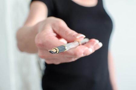 Woman showing a pen, closeupの写真素材