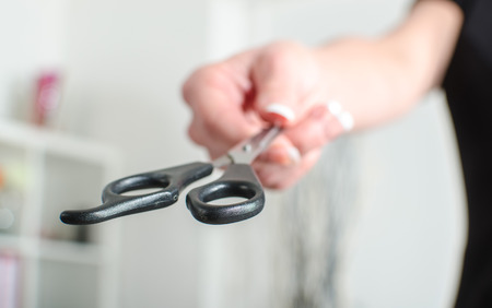 Woman hand showing a pair of scissors, closeupの写真素材