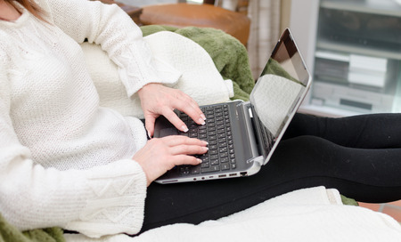 Woman sitting on a sofa and using a computerの写真素材