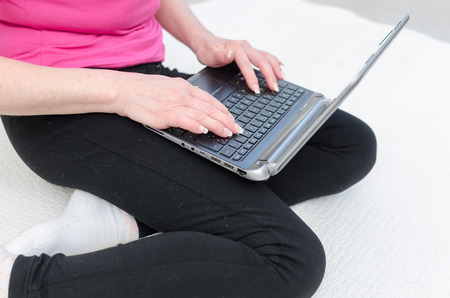 Relaxed woman sitting on a carpet using a computerの写真素材