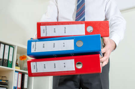 Businessman holding a pile of binder at officeの写真素材