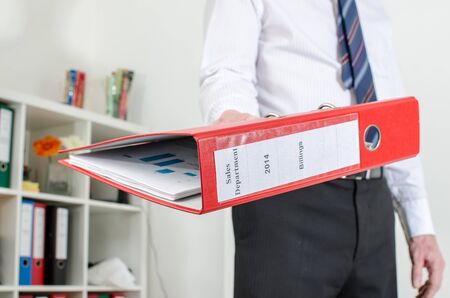 Businessman holding a red binder at officeの写真素材