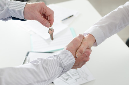 shaking hands with his client by delivering the keysの写真素材
