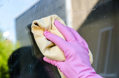 Gloved hand cleaning window, closeup