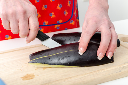 Hands of woman cutting eggplant on wooden boardの写真素材