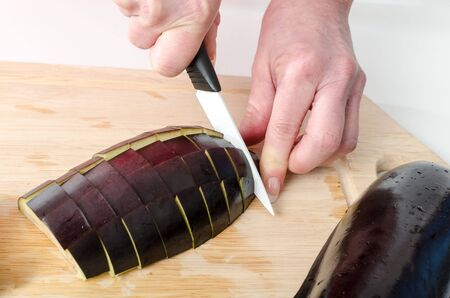 Hands of woman cutting eggplant on wooden boardの写真素材