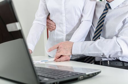 Manager holding his secretary around the waist, at the officeの写真素材