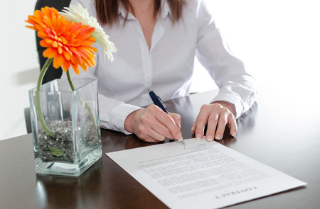 Businesswoman signing a document at officeの写真素材