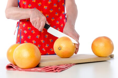 Woman cutting a grapefruit on a boardの写真素材