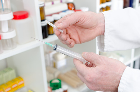 Doctor holding a syringe in medical officeの写真素材