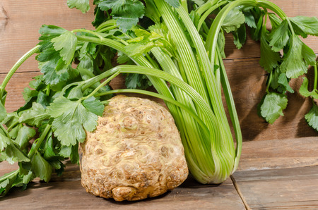 Celery root and green celery on wooden background