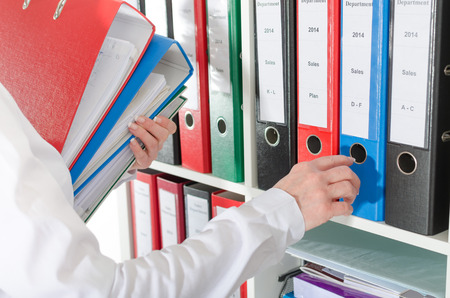 Businesswoman taking binders from a shelf at officeの写真素材