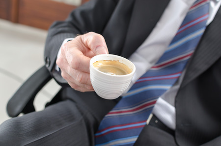 Businessman holding a cup of coffee at officeの写真素材