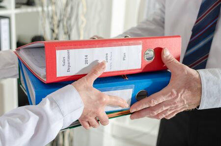Secretary giving binders to her manager at officeの写真素材