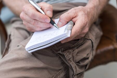 Man sitting outdoor taking notes on a pocket bookの写真素材