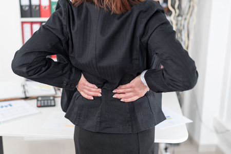 Businesswoman suffering from back pain at officeの写真素材