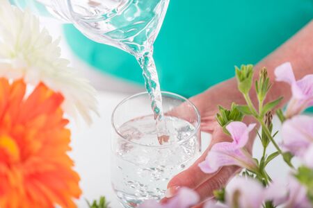 Pouring water from a pitcher into a glassの写真素材