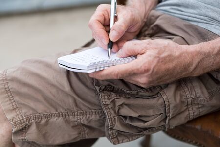 Man sitting outdoor taking notes on a pocket bookの写真素材