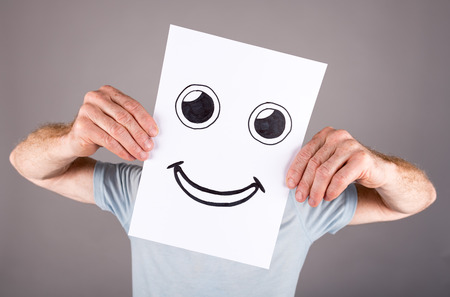 Man holding a paper with a face having a joy expressionの写真素材