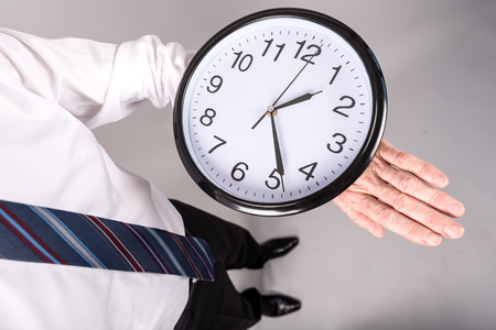Businessman standing, looking at his large watch