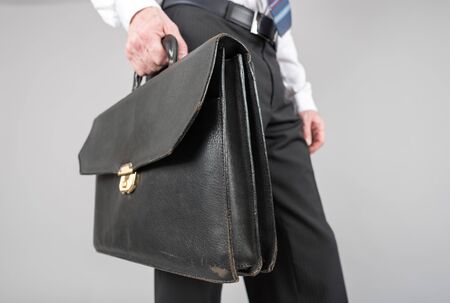 Businessman holding a briefcase, isolated on greyの写真素材