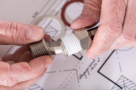 Plumber screwing plumbing fittings, closeup