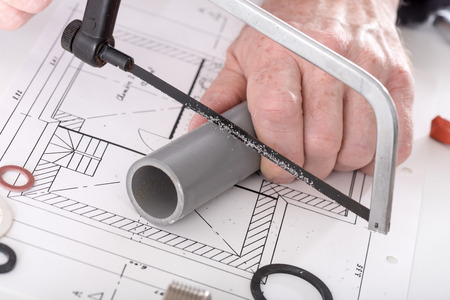 Plumber sawing a pvc pipe on a planの写真素材