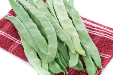 Fresh flat green beans on a red towel