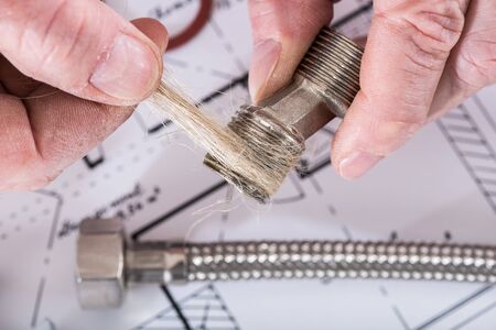 Plumber putting hemp fibers on a thread, closeup