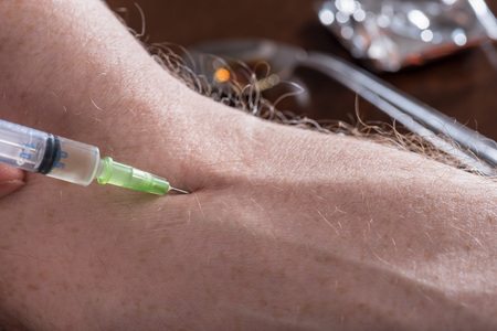 Junkie injecting a dose of heroin in his arm, closeupの写真素材