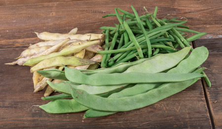 Green, runner and coco beans on wooden background