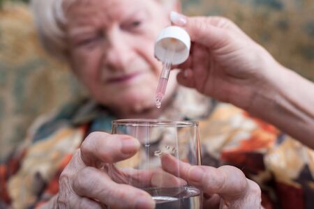 Medical assistant giving a drug to an old womanの写真素材