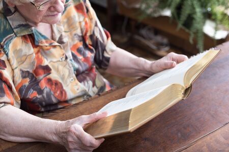 Old woman reading a book at home