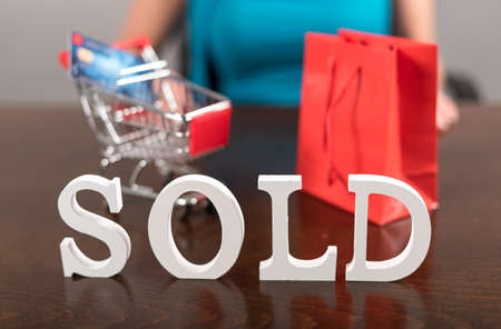 Sold sign with a shopping trolley and a bagの写真素材