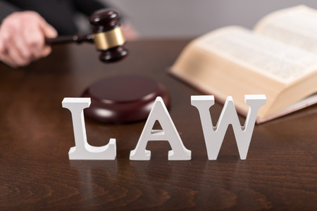 Law concept with hand holding a judge gavelの写真素材