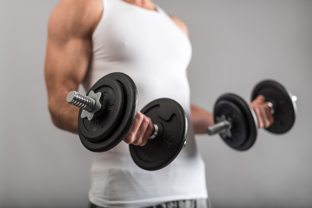 Athletic man working with heavy dumbbellsの写真素材