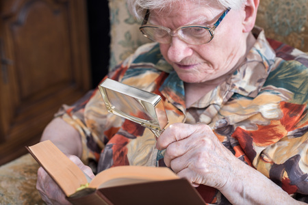 Old woman reading a book with a magnifying glassの写真素材