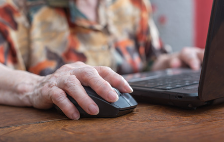 Old woman hand using the mouse of a computerの写真素材