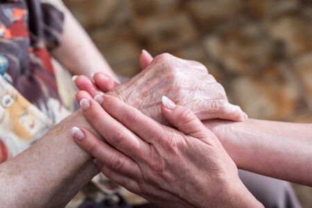 Hands of young woman holding the hands of an elderly personの写真素材