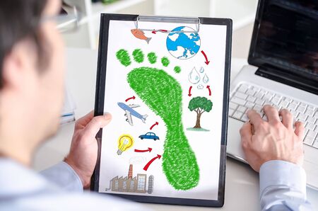 Man holding a clipboard with carbon footprint conceptの写真素材